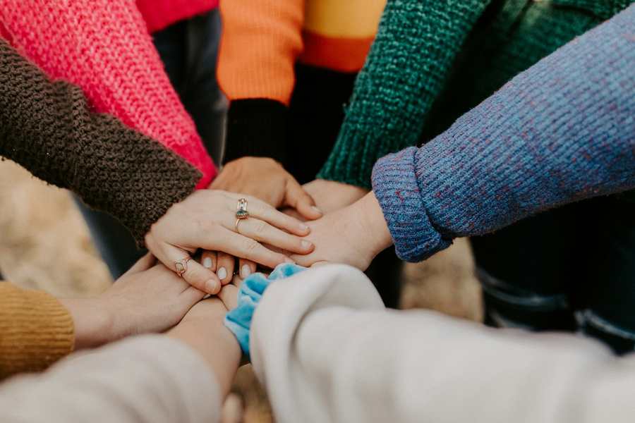 A diverse group placing their hands together